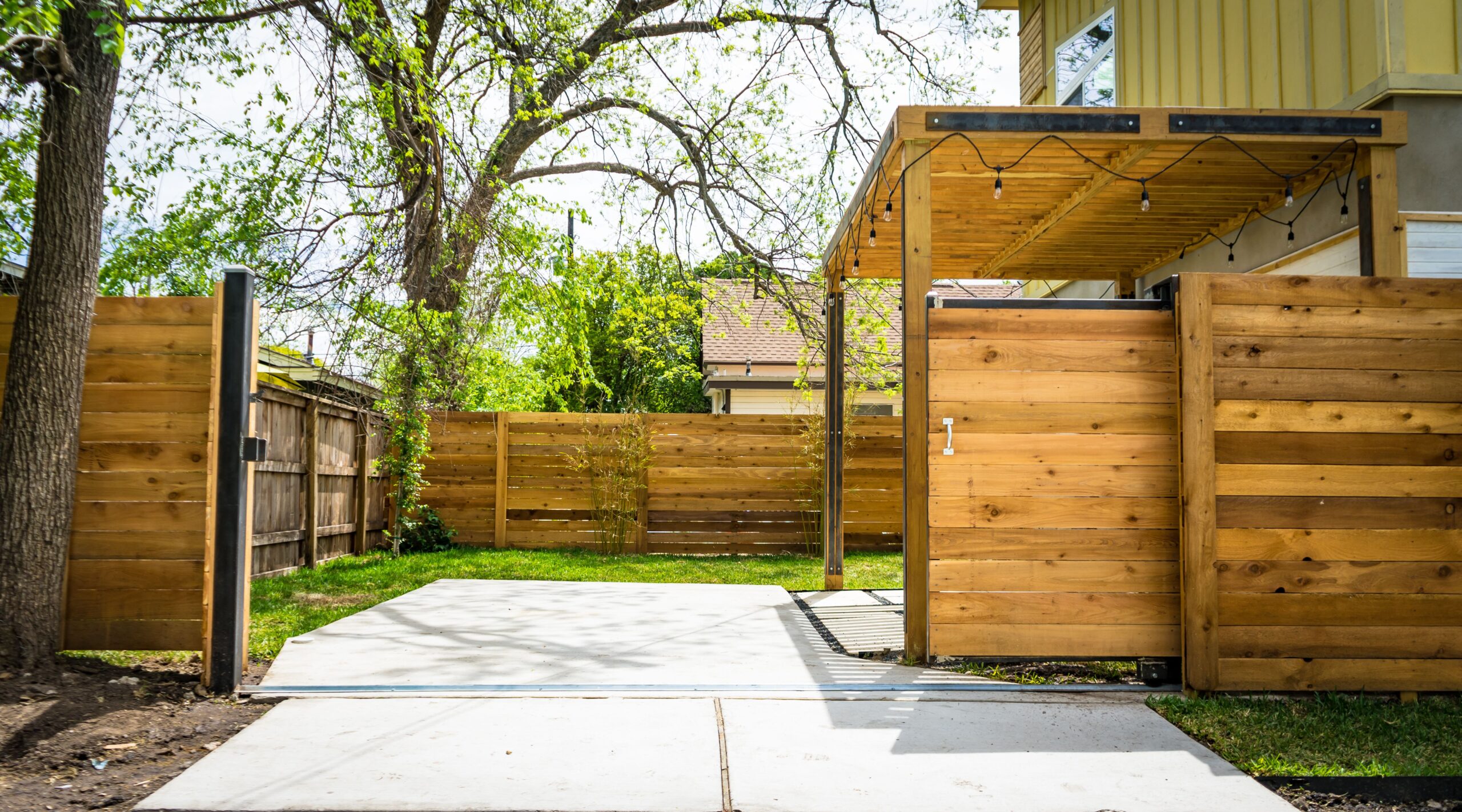 Sunlit wooden fence and patio gate creating privacy in a peaceful backyard.