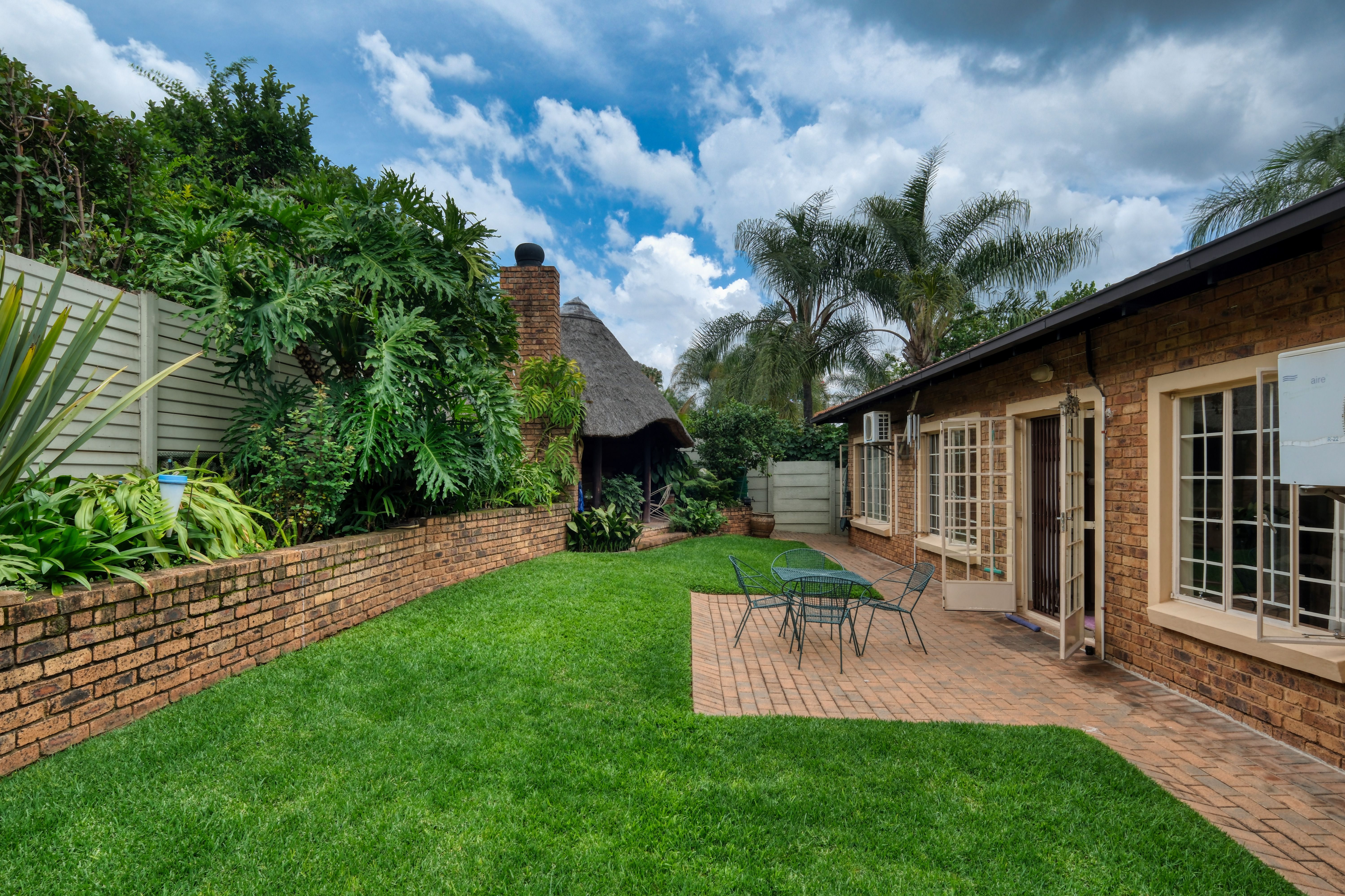 Inviting backyard patio with table and chairs surrounded by lush greenery.